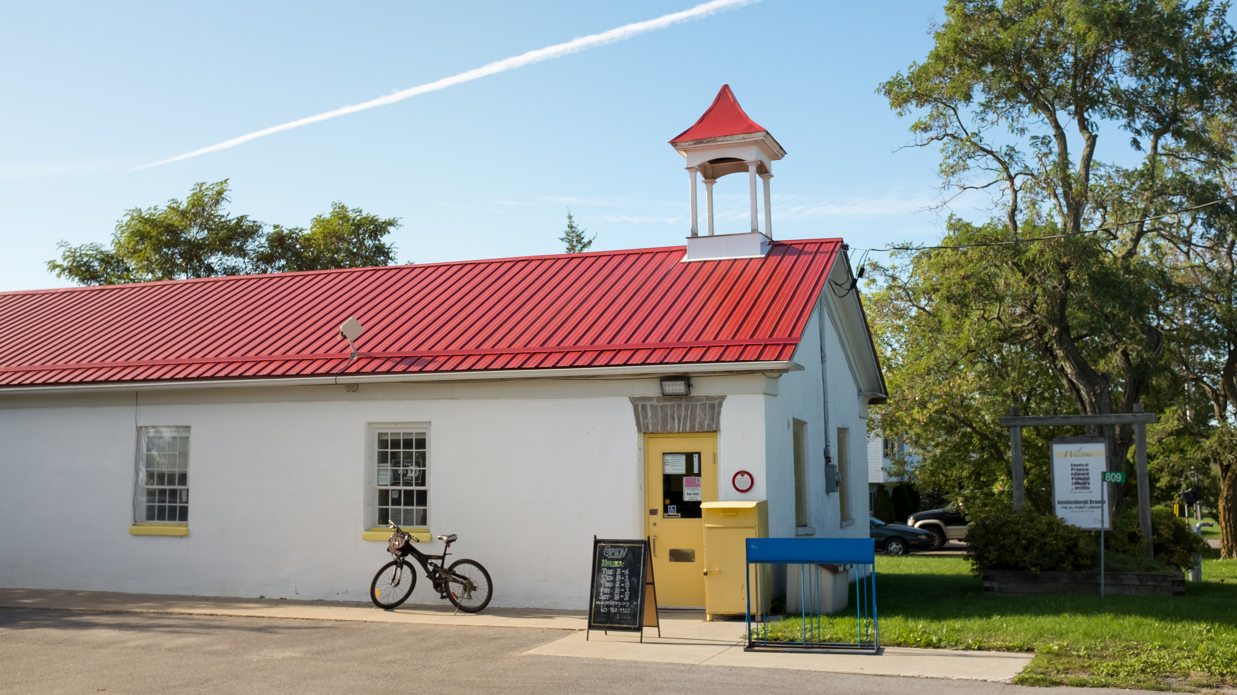 The Ameliasburgh Branch Library with red roof, white walls and blue sky in the background