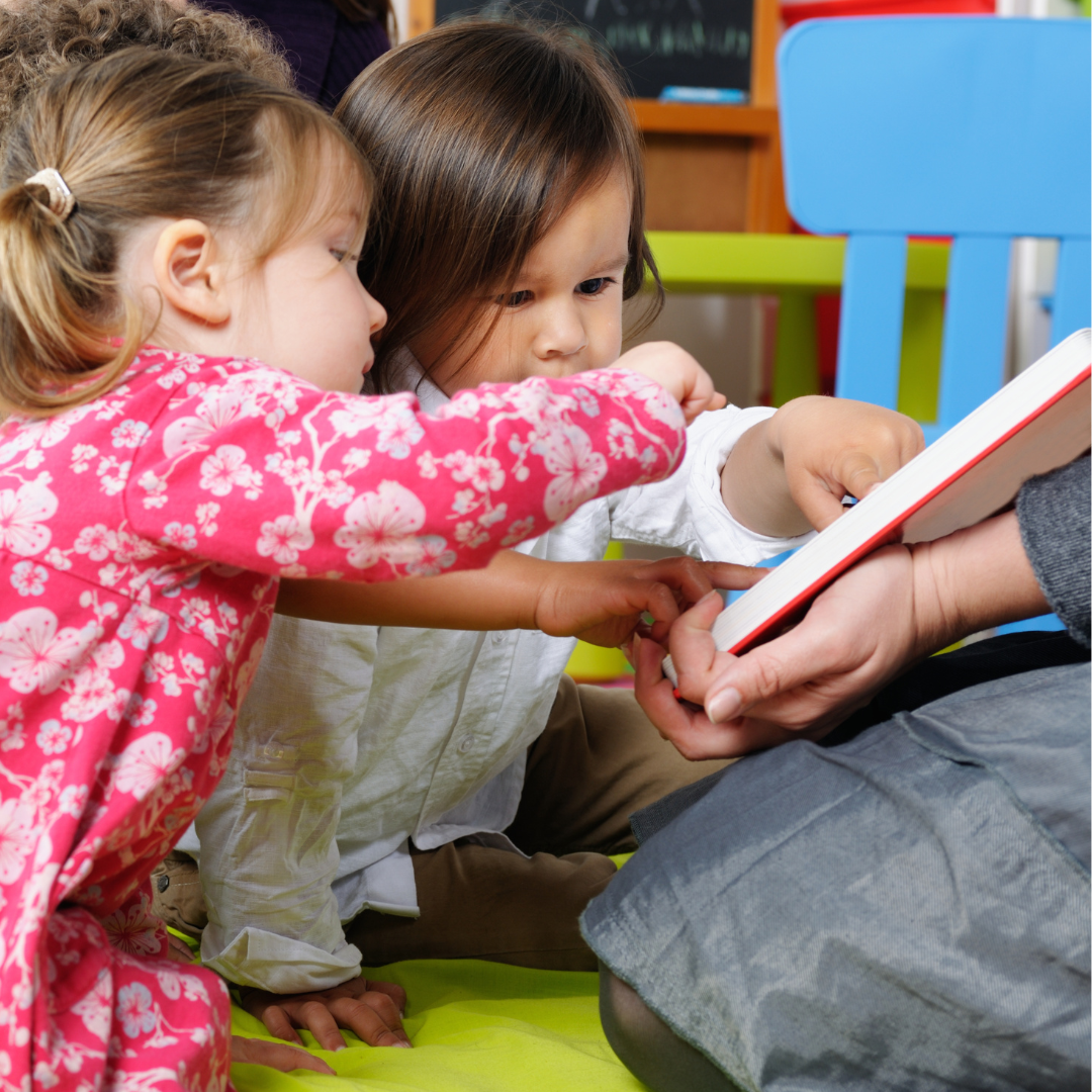 Two toddlers being read a story